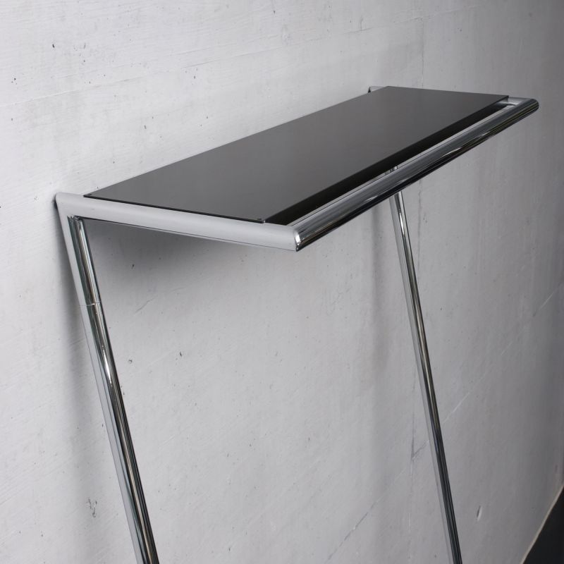 Hutablage für Zen Garderobe: Schwarze Ablage mit verchromtem Gestell vor einer Wand.